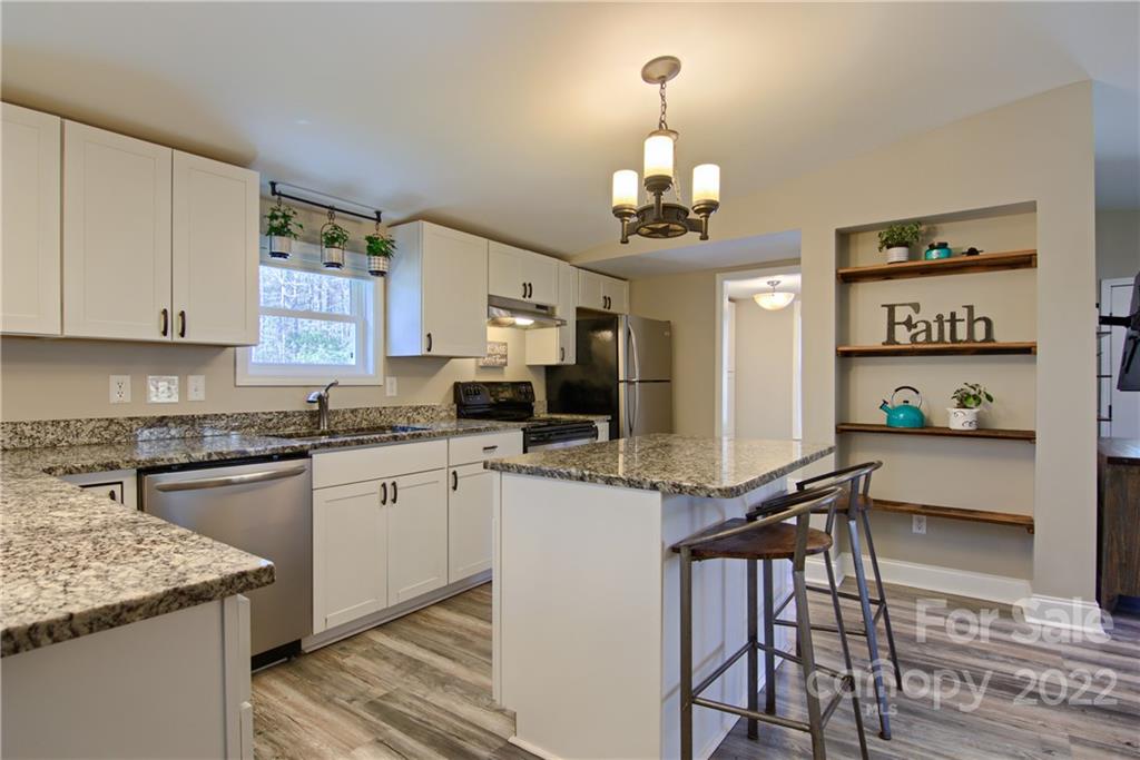 20 Cascade Village Road, Unit 2 Pisgah Forest, NC 28768 - Photo 7 of 36 a kitchen with granite countertop stainless steel appliances a sink stove and white cabinets