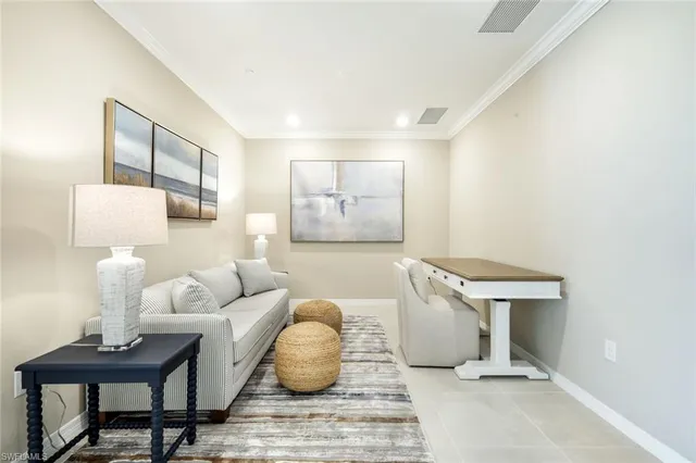 a living room with furniture a lamp paintings and a window