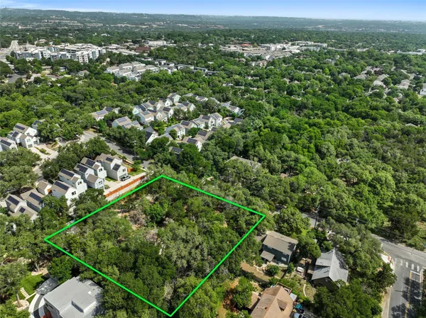 an aerial view of residential houses with outdoor space and trees