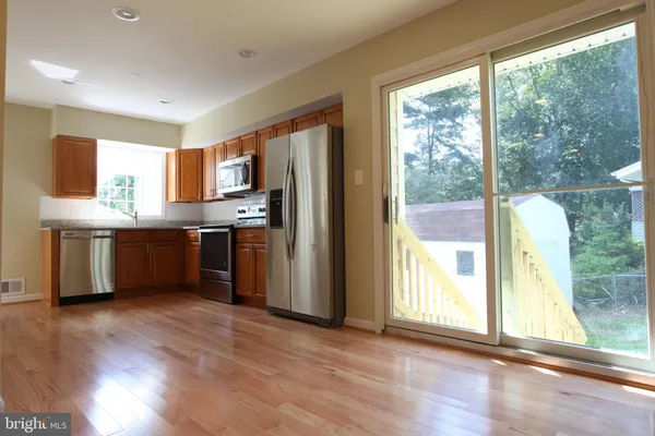 a kitchen with stainless steel appliances granite countertop a refrigerator a sink a stove and a wooden floors