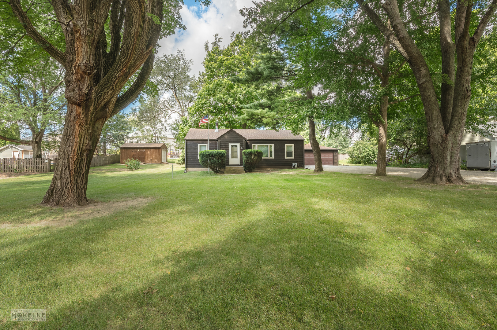 a view of a house with a big yard and large trees