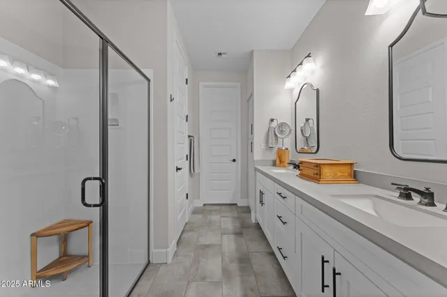 a spacious bathroom with a double vanity sink a mirror and shower