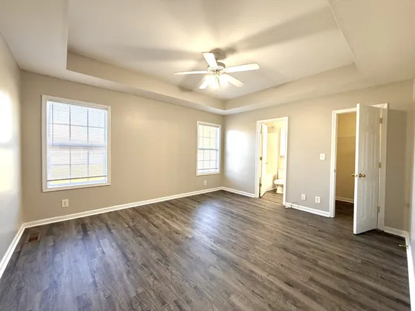 a view of an empty room with wooden floor and window