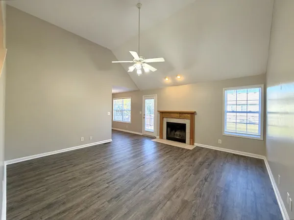 an empty room with wooden floor fireplace and window