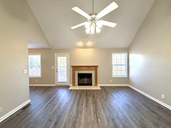 an empty room with wooden floor fireplace and windows