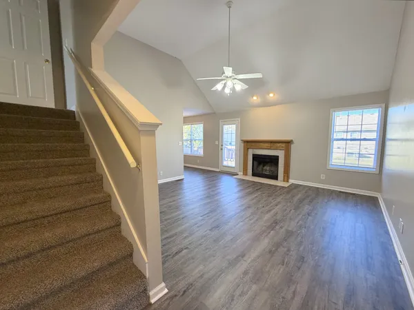 an empty room with wooden floor fireplace and windows