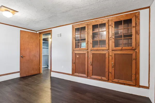 an empty room with wooden floor and cabinet