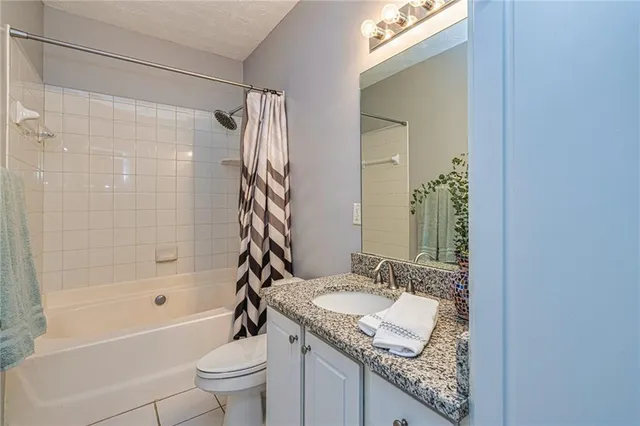 a bathroom with a granite countertop sink a toilet and shower