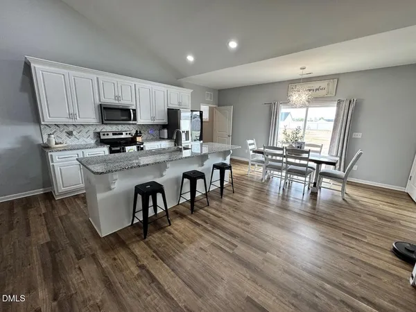 a kitchen with stainless steel appliances a dining table chairs stove a refrigerator and cabinets