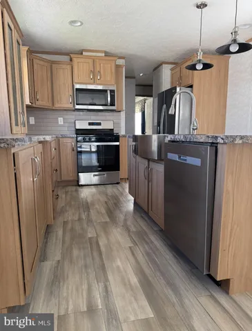 a kitchen with stainless steel appliances granite countertop a refrigerator a stove a sink and a microwave