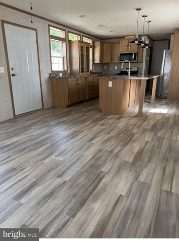 a kitchen with stainless steel appliances kitchen island granite countertop a refrigerator a sink dishwasher a stove and a dining table with wooden floor