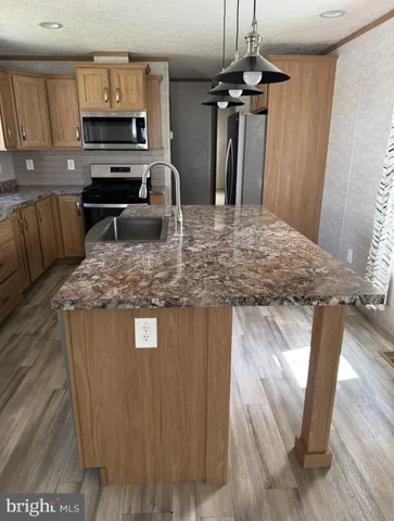 a kitchen with kitchen island granite countertop a stove top oven a sink dishwasher a dining table and chairs with wooden floor