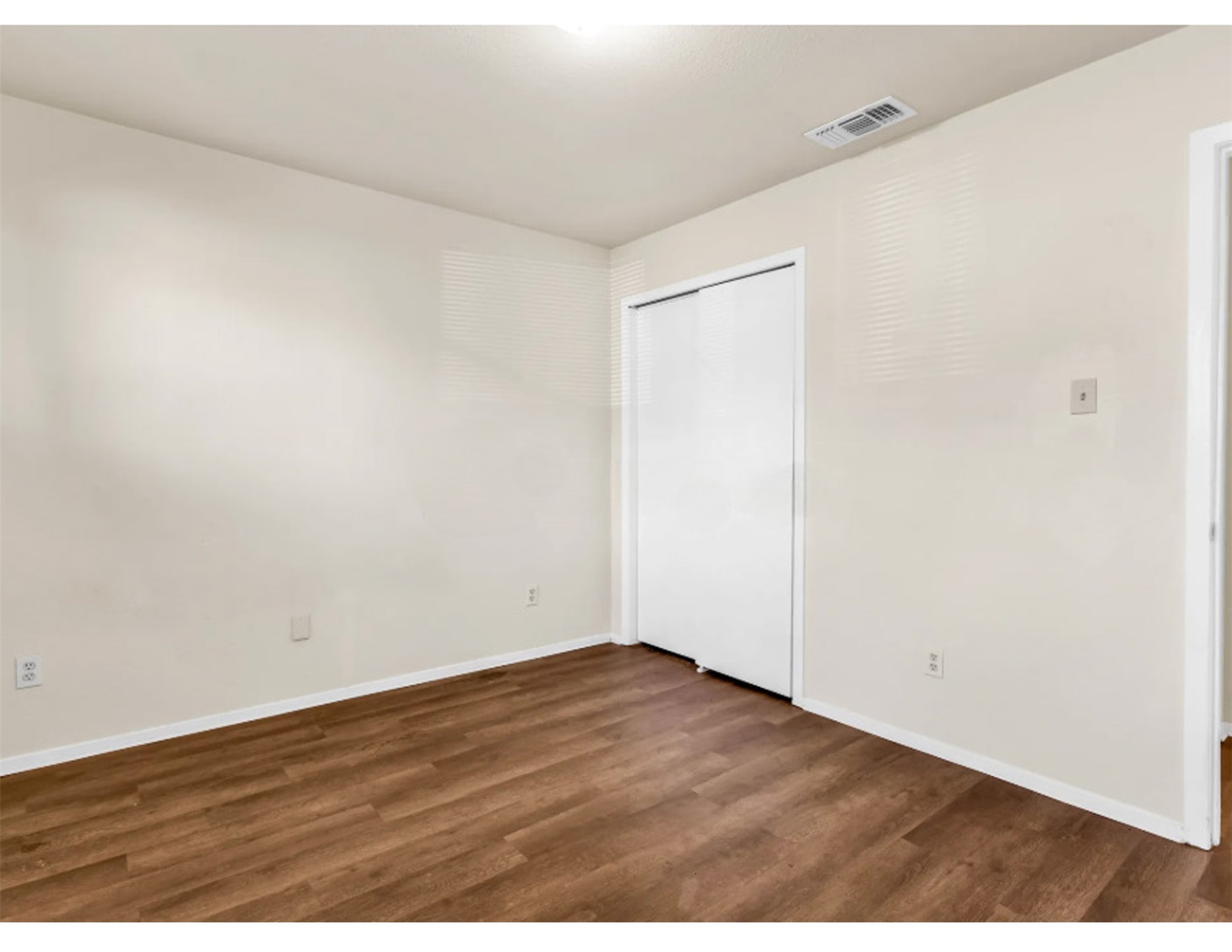 2012 West Loop Austin, TX 78758 - Photo 12 of 16 Unfurnished bedroom featuring visible vents, baseboards, and wood finished floors