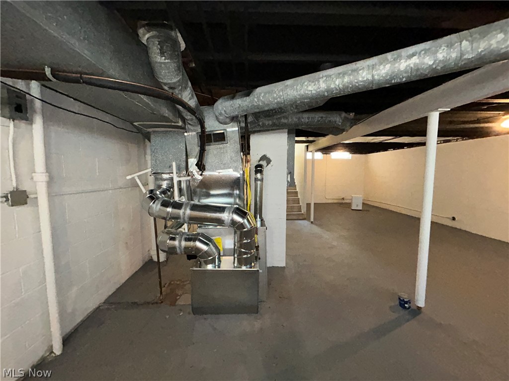 9316 Alexander Road Garfield Heights, OH 44125 - Photo 20 of 27 Galvanized steel ductwork, painted concrete block walls, painted concrete flooring, exposed ceiling joists, and a utility staircase