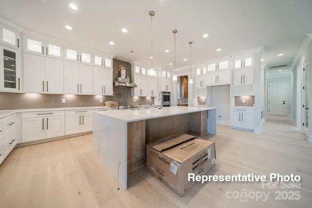 a large white kitchen with kitchen island a sink a center island stainless steel appliances and a counter top