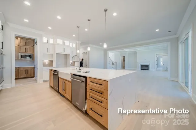 a large white kitchen with a large counter top a sink a stove and a refrigerator