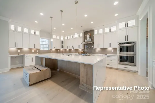 a large white kitchen with kitchen island a sink stainless steel appliances and cabinets