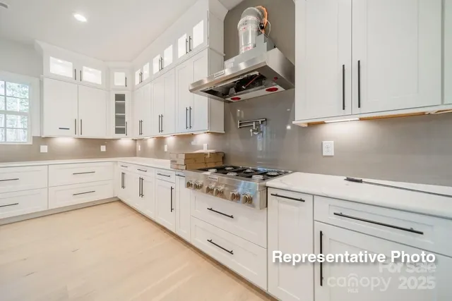 a kitchen with stainless steel appliances granite countertop a sink a stove a refrigerator and white cabinets