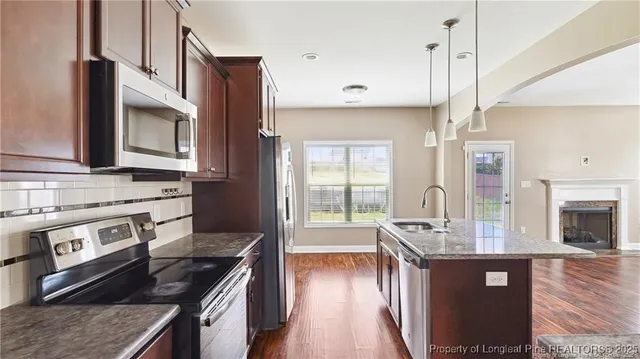 a kitchen with stainless steel appliances granite countertop hardwood floor sink stove and granite counter top