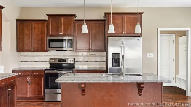 a kitchen with kitchen island granite countertop a sink cabinets and stainless steel appliances
