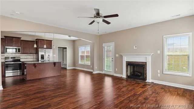 a view of an empty room with a kitchen and a window