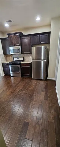 a view of kitchen with wooden floors and stainless steel appliances