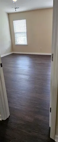 a view of an empty room with window and wooden floor