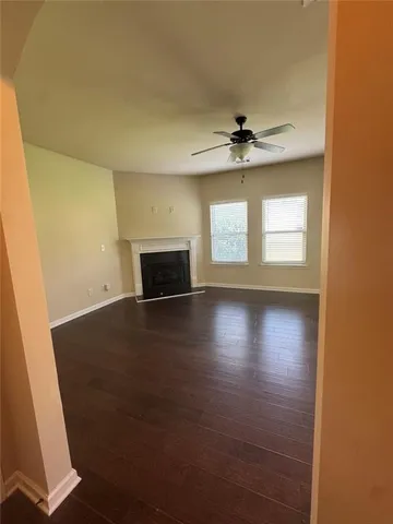 an empty room with wooden floor fireplace and windows