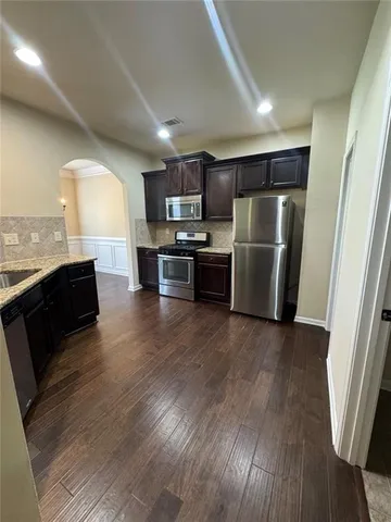 a kitchen with a refrigerator a stove top oven a sink dishwasher and wooden floor