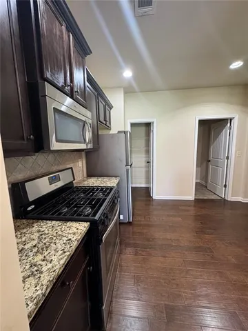 a kitchen with granite countertop a stove and a microwave