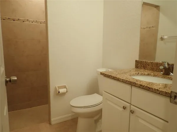 a bathroom with a granite countertop toilet and a sink