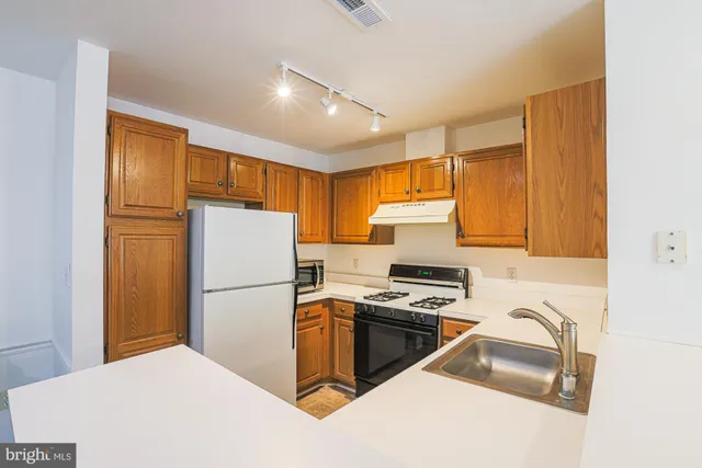 a kitchen with a sink a counter top space stainless steel appliances and cabinets