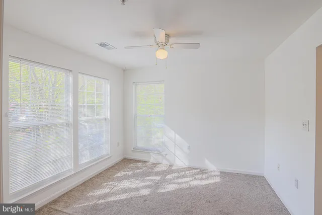 an empty room with windows and fan