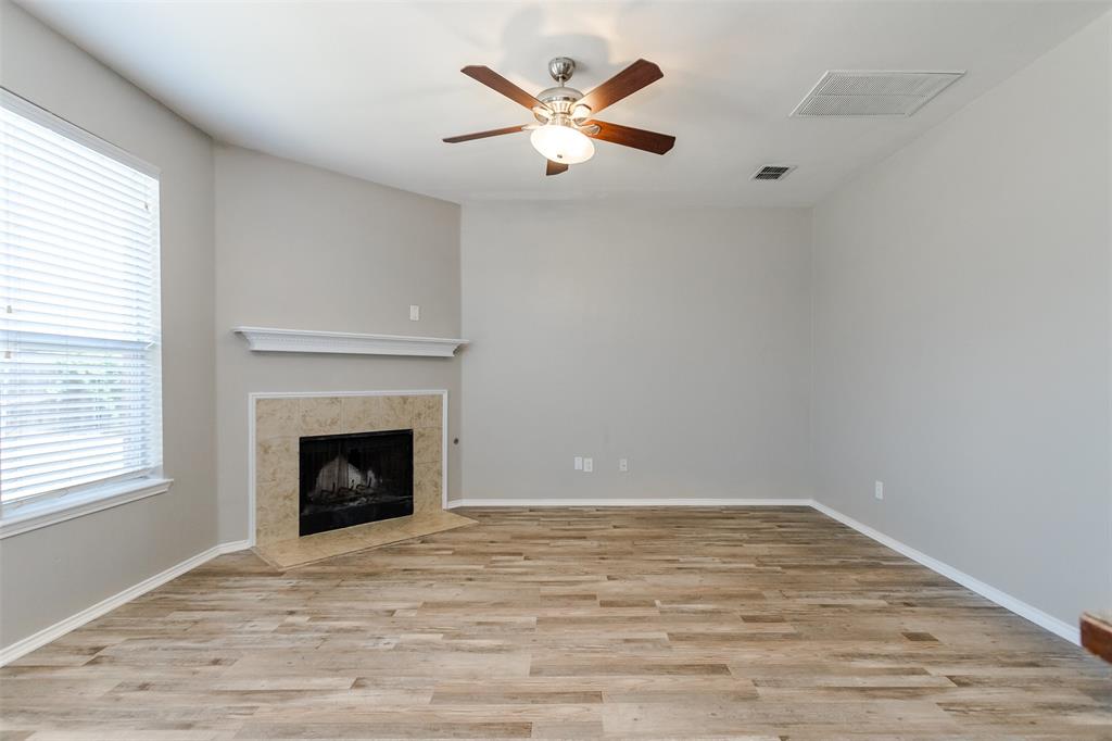 203 Arabian Road Waxahachie, TX 75165 - Photo 7 of 24 Living space featuring wood-finish flooring, a corner fireplace with stone surround, a white mantel, and a ceiling fan with light fixture