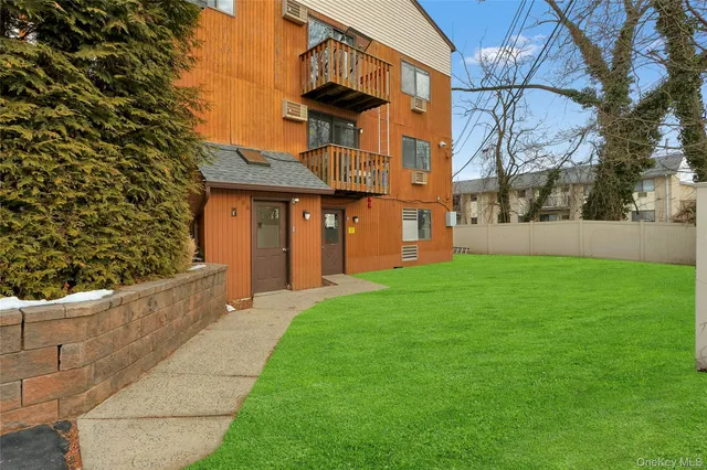 a view of a house with brick walls plants and large tree