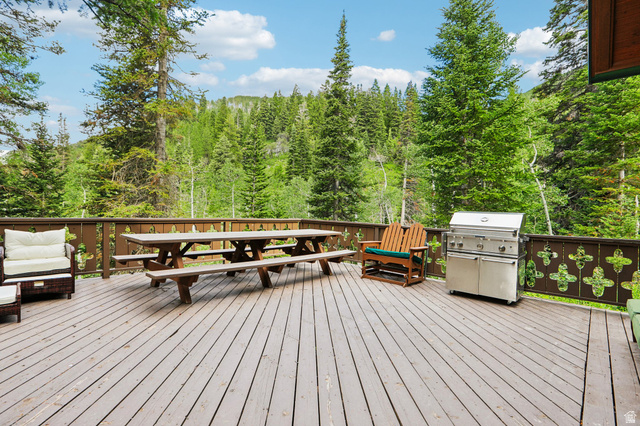 10205 East Moose Loop Road Salt Lake City, UT 84121 - Photo 41 of 50 Spacious outdoor deck featuring natural wood decking, a decorative wood railing, and a serene forest backdrop