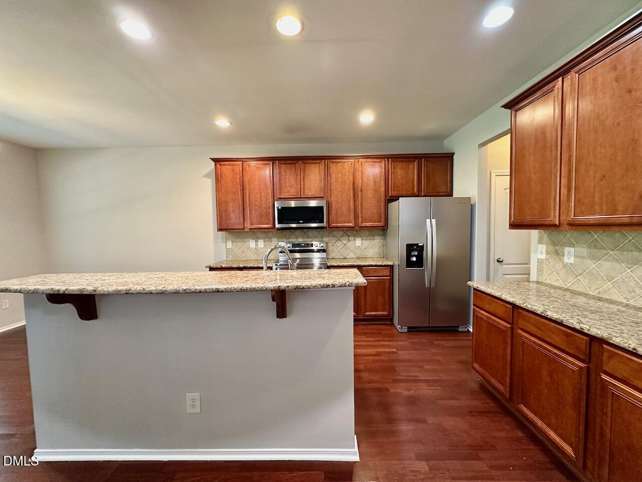 8208 Stone Cellar Drive Raleigh, NC 27613 - Photo 11 of 34 a kitchen with stainless steel appliances granite countertop a stove a sink a refrigerator a center island and a refrigerator