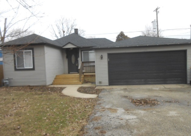 a view of a house with a small yard and garage