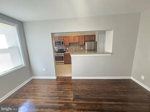 a view of a kitchen with wooden floor and a window