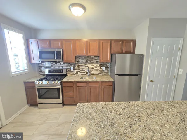 a kitchen with stainless steel appliances granite countertop a refrigerator sink and stove