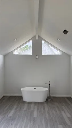 a view of an empty room with wooden floor and window
