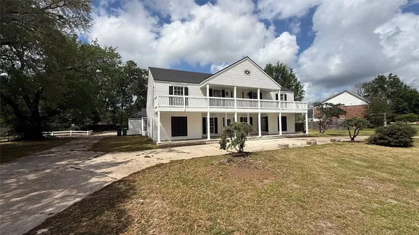 a view of house with a big yard and large trees