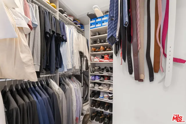a view of walk in closet with clothes and shoes