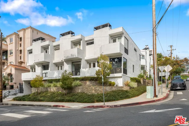 a view of a white building among the street and palm trees
