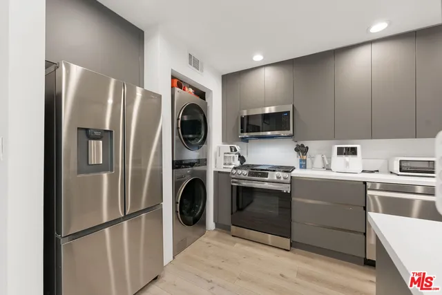 a kitchen with stainless steel appliances granite countertop a refrigerator a stove top oven a sink and dishwasher