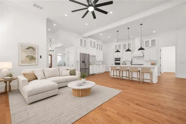 a living room with furniture kitchen view and a wooden floor