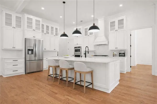 a kitchen with stainless steel appliances granite countertop a sink a stove a refrigerator and island with wooden floor