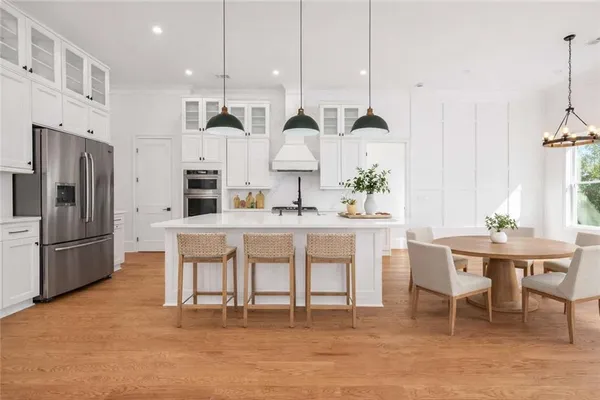 a kitchen with stainless steel appliances kitchen island granite countertop a table chairs and a sink