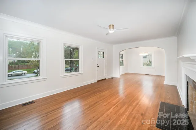 a view of empty room with wooden floor and fan