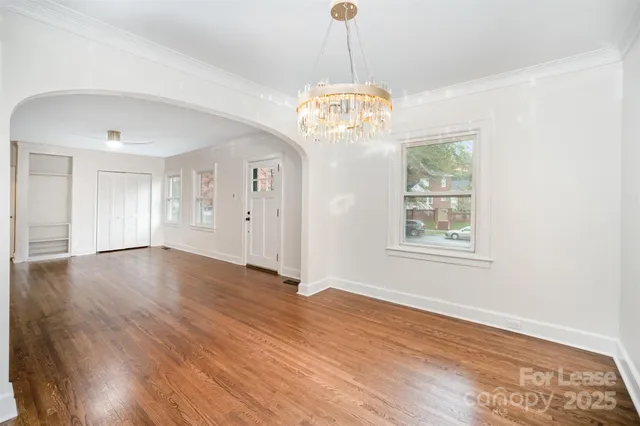 a view of a livingroom with a chandelier wooden floor and windows